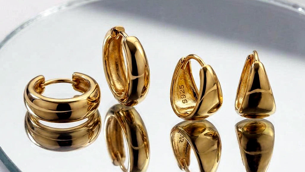 Set of gold hoop earrings on a reflective surface