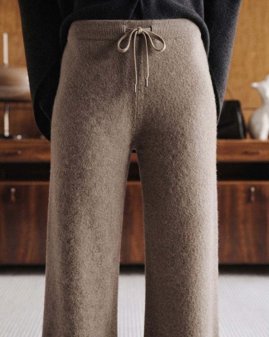 Close-up of a person wearing textured knit wide-leg pants in taupe brown with a matching drawstring waist, paired with a dark sweater in an indoor setting.